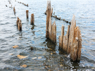 Salty estuary Kuyalnik, dead lake near Odessa, Ukraine. Wooden sticks reflected in blue water at sunny weather.