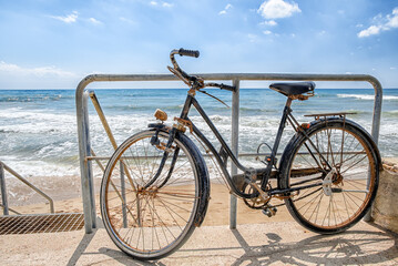 Fototapeta premium Old retro style bike parked on a sandy beach on a backgrouns of blue sea