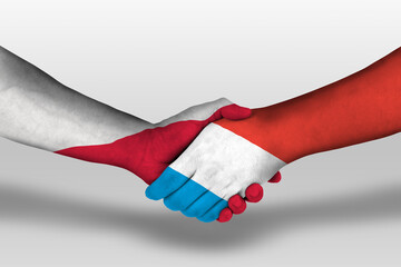 Handshake between luxembourg and poland flags painted on hands, illustration with clipping path. - obrazy, fototapety, plakaty