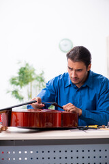 Young male repairman repairing cello
