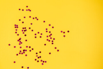 Abstract background of falling pink stars on yellow paper.
