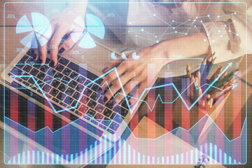 Double exposure of woman hands typing on computer and forex chart hologram drawing. Stock market invest concept.
