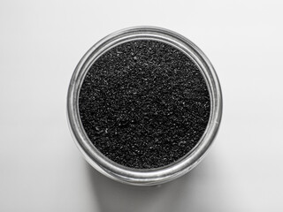 Black activated charcoal powder in a glass. Superfood, ingredient for cosmetics and vegan, vegetarian food, detox concept. White background. Copy space, selective focus