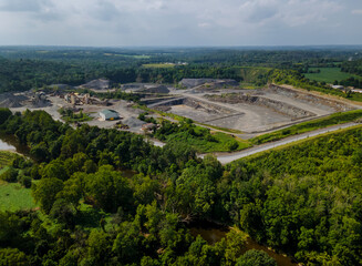 Fototapeta na wymiar Aerial view of opencast mining quarry with lots of machinery at work in middle of forest on Pennsylvania, USA
