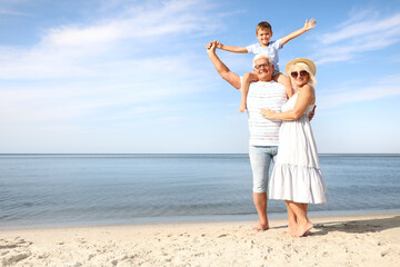 Cute little boy with grandparents spending time together on sea beach