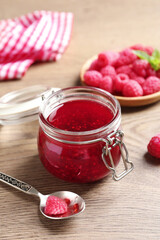 Sweet raspberry jam and fresh berries on wooden table