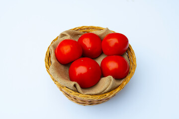 Fresh red tomatoes in wicker basket isolated on white background