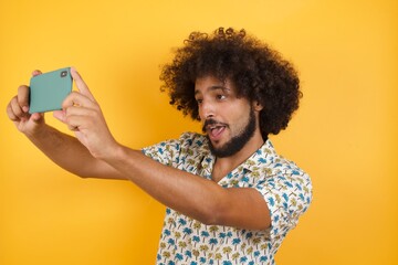 Close-up portrait Young man with afro hair over wearing hawaiian shirt standing over yellow...