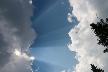  heavenly light rays passing through clouds in blue sky