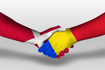 Handshake between romania and denmark flags painted on hands, illustration with clipping path.