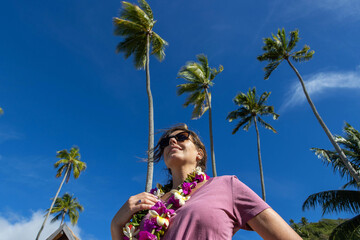 Beautiful woman under tall palm trees on a tropical island