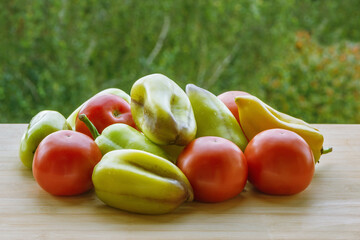 Red fresh tomatoes and green sweet pepper on wooden table.