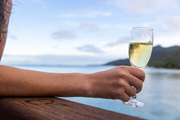 A woman drinks a glass of cold champagne on a tropical island vacation