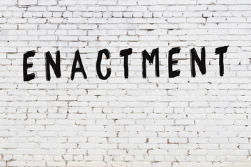 White wall with black paint inscription enactment on it