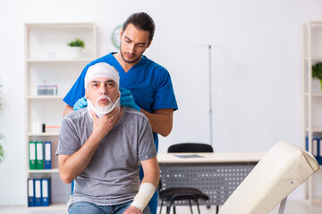 Fototapeta premium Young male doctor and old patient in first aid concept