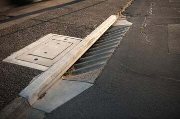 Fototapeta premium Gutter of a stormwater drainage system in perspective on the side of an road with markings. Australia. Melbourne. 