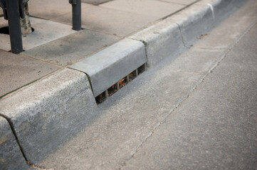 Gutter of a stormwater drainage system in perspective on the side of an road with markings. Australia. Melbourne. 
