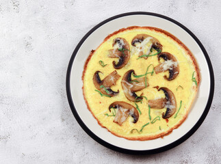 Omelet with mushrooms on a round plate on a light gray background. Top view, flat lay