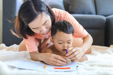 Asian mom teaching her baby boy draw