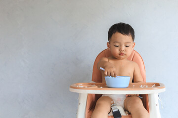 Asian baby boy eating food by himself