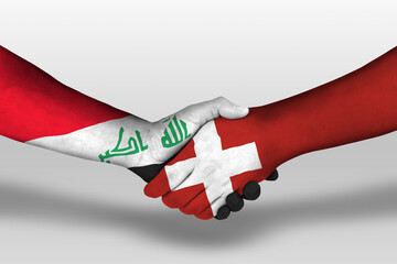 Handshake between switzerland and iraq flags painted on hands, illustration with clipping path.