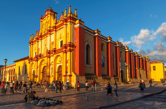 Mexican city life with street vendors and people by the Cathedral facade at sunset, San Cristobal de las Casas, Mexico.