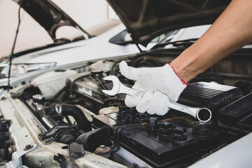 Obraz premium Close-up hand of auto mechanic using wrench to repair a car engine. concepts of car care fix repair service and insurance.