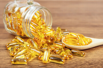 A pile of cod liver oil capsule in a wooden spoon. Dietary supplement for health-care concepts.