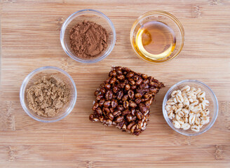 Large puffed wheat square treat with small glass bowls of raw ingredients beside; delicious and chewy puffed wheat squares