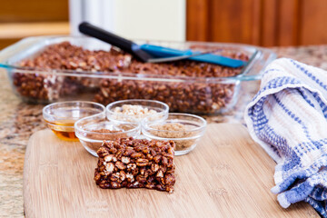 Large puffed wheat square treat with small glass bowls of raw ingredients beside; delicious and chewy puffed wheat squares