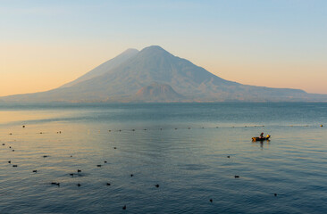 Fisherman checking nets for fish in the Atitlan Lake at sunrise with the Toliman and Atitlan volcano in the background, Panajachel, Guatemala.