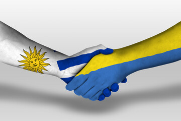 Handshake between ukraine and uruguay flags painted on hands, illustration with clipping path.