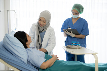 Asian female doctor wearing protective gears examination and treating patient in a hospital room