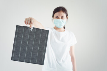 Asian woman wearing a hygiene protective face mask during changing a dirty air filter.