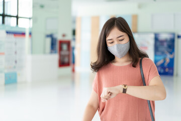 Beautiful Asian business woman walking in the hall during the rush hour and looking at her watch close up with copyspace in left side. Worried Asian businesswoman fast walking in the airport terminal.