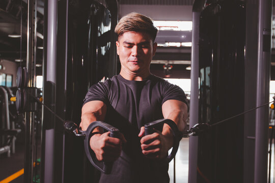Strong and powerful Asian athletes training a cable fly workout at the indoor gym, a muscle building exercise. 