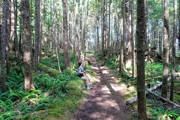 A woman resting during a hard hike through the forests of cape scott provincial park, vancouver island, british columbia, canada