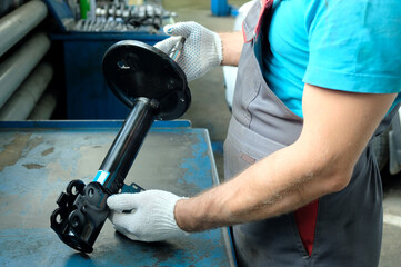In the hands of a car mechanic, a new shock absorber strut. Repair and maintenance of the car in...