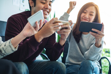 A group of young people having fun and celebrating while watching and playing games on mobile phone together © Farknot Architect