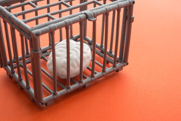 Brain in cage on orange background with copy space. Creativity idea, human rights or freedom thinking concept.