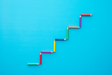 Color pencils staircase form on blue background with copy space. Business, creative idea, kids art education and development concept.