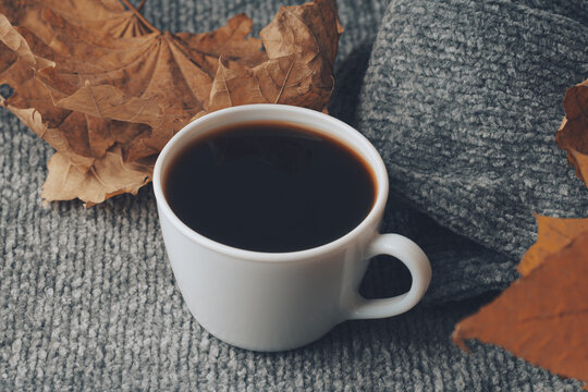ellow orange fall leaves, hot steaming cup of coffee and a warm scarf