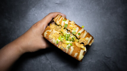 Hand grabbing garlic sauce meat toast in closed-up view for social media, restaurant or cafe menu