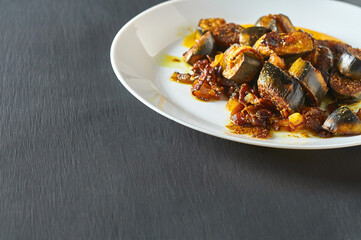 Served dish of fried bananas with onion and curry in restaurant on concrete table