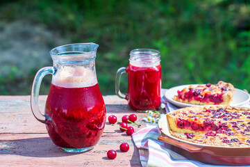 Homemade cherry pie and red cherry drink on the wooden table in garden