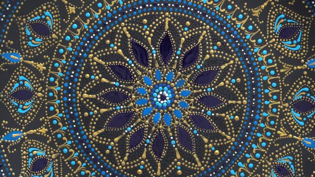 Decorative ceramic plate with black, blue and golden colors, painted plate on background, closeup, top view, rotate. Decorative porcelain plate painted with acrylic paints, handwork, dot painting