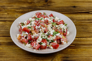 Tasty salad of tomato, cottage cheese, dill and olive oil on wooden table