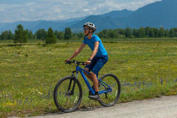 A young man on a mountain bike travels through the picturesque places of the Altai mountains.