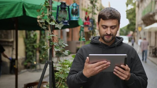 Urban man using tablet computer outside app on 5g wireless device. Casual young professional male in late 20s. Hand touching digital screen pad pc