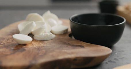 sliced small mozzarella balls on olive wood board